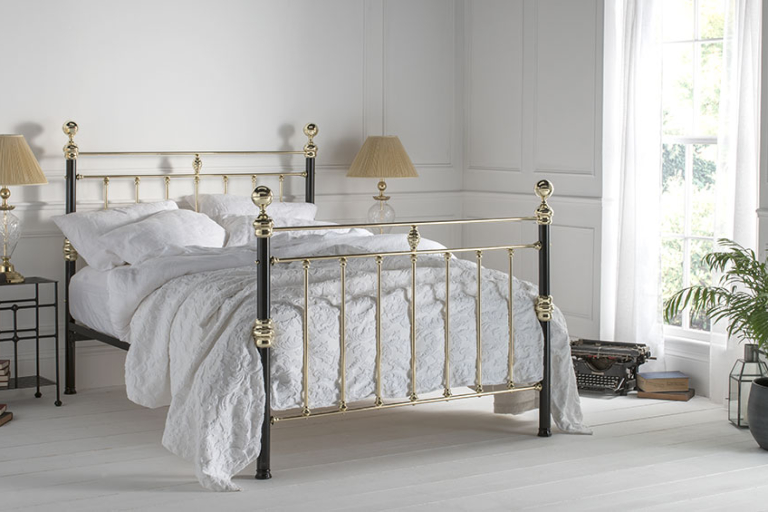 George bed with polished brass detailing and black iron posts in a classic white bedroom