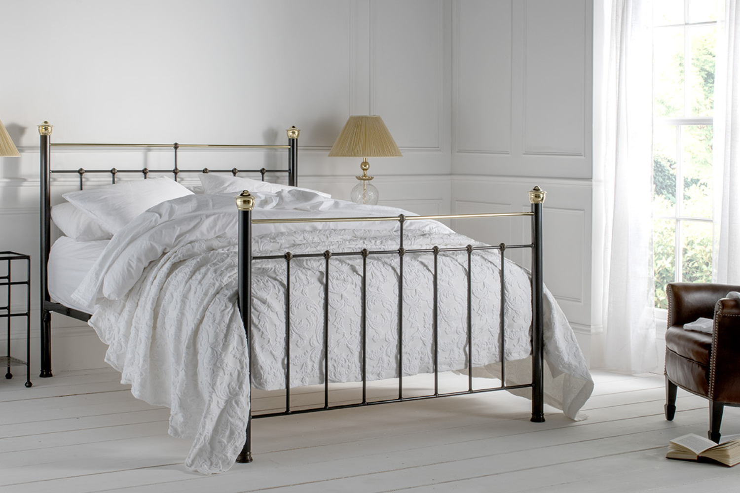 Beatrice black iron bed with brass finials and white bedding in a classic bedroom interior