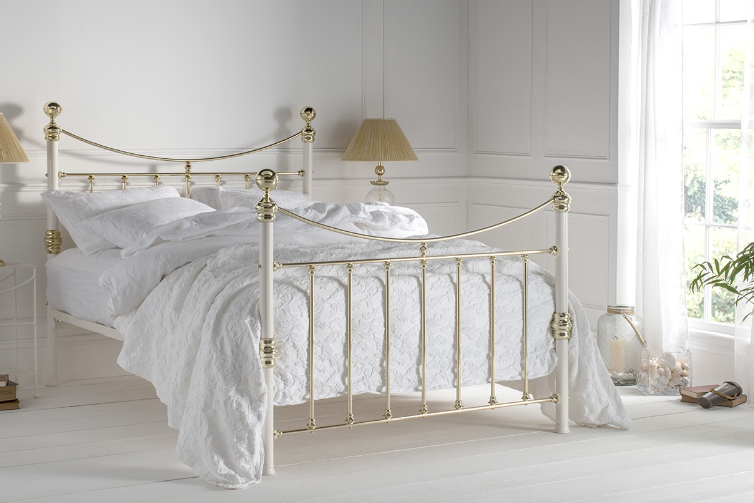Elizabeth brass bed frame with curved top rail and ornate finials in a white airy bedroom
