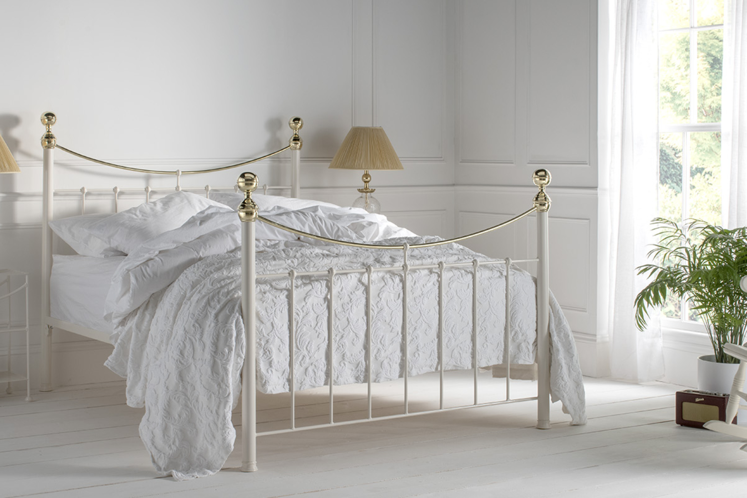 Victoria brass bed with tall corner posts and decorative finials in a bright classic bedroom