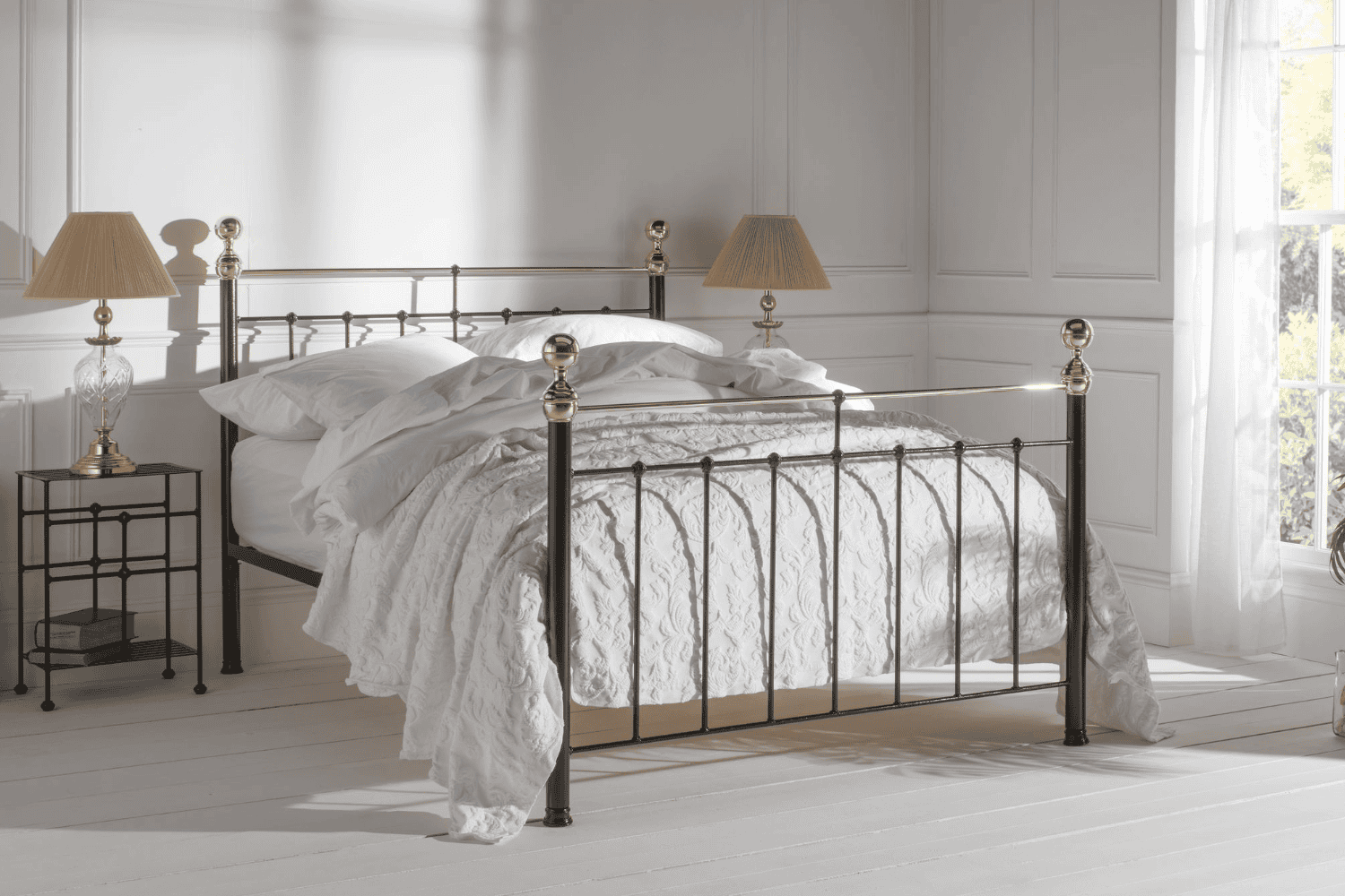 Albert bed frame with black iron structure and brass finials, styled in a white minimalist bedroom