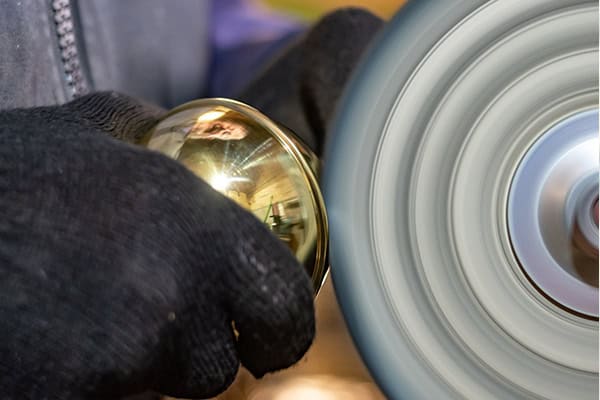 Craftsman polishing a brass finial to finish a handmade bed