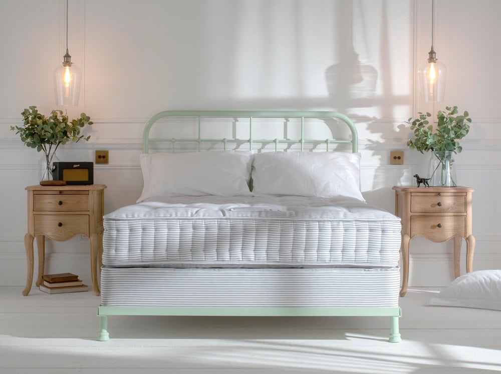 natural fibre british made wool mattress sitting on a sprung divan base, featuring a mint green dormatory style iron bed headboard