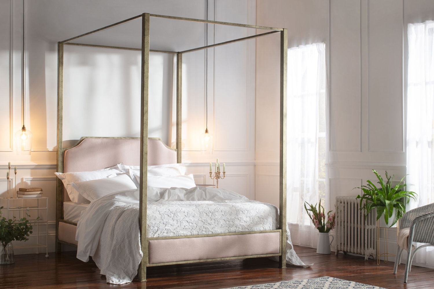 Aurora four-poster bed with metallic frame and blush upholstered headboard, styled in an elegant master bedroom with soft lighting