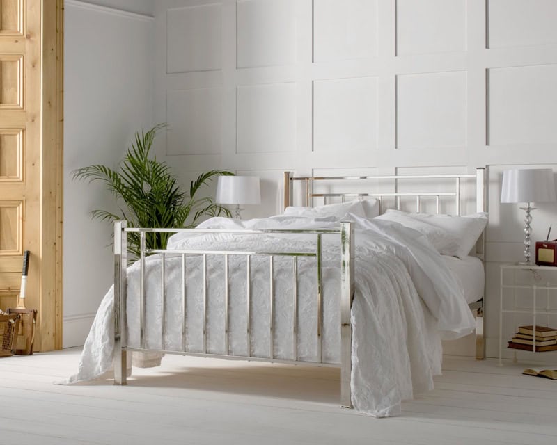 geometric inspired art deco inspired nickel bed with a high polished finishes dressed in white bed linen