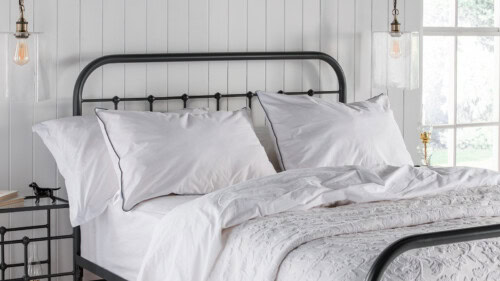 white cotton washable pillow covers displayed on a dark grey dormitory style iron bed frame, accompanied by white bedlinen.